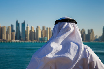 Modern buildings in Dubai Marina,, UAE. Man in Arab dress looks