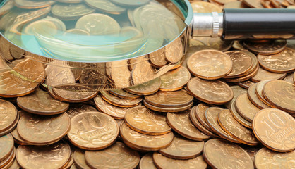 magnifying glass on a heap of coins