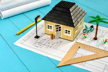Toy house (constructor) on table with the drawings and business accessories