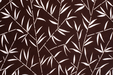 Bamboo leaves pattern on brown fabric. Tropical leaves print as background.