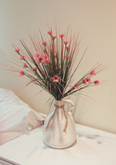 Artificial flowers in a vase on the bedside table. Interior