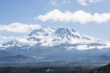 Fototapeta na wymiar Snowcapped Mount Shasta volcano during winter with valley view and clouds on mountain