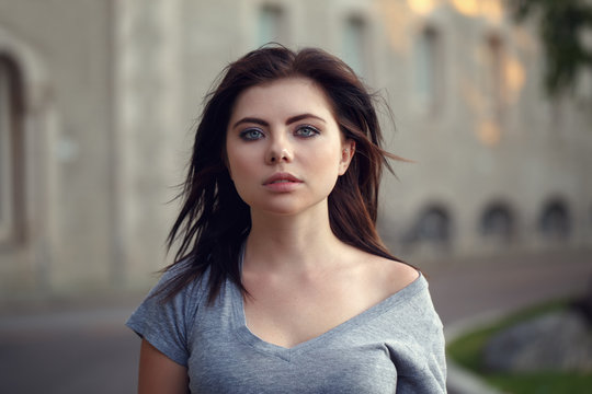 Closeup portrait of beautiful young sexy Caucasian woman with red black hair, blue eyes, looking in camera, outdoors on sunset, summer evening, natural beauty youth look