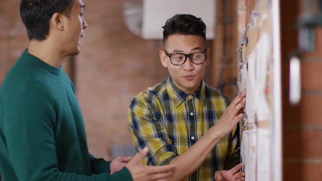  Cheerful hipster business people looking at pin board in creative office