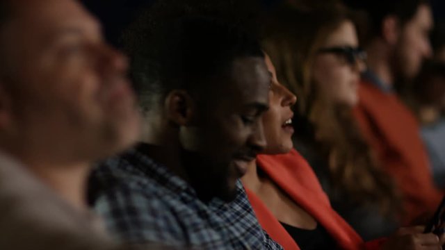  Couple watching a film with 3D glasses in crowded movie theatre