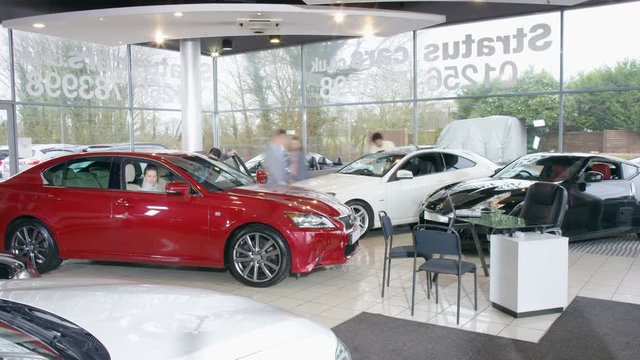  Time lapse of salesman & customers in busy car dealership. 
