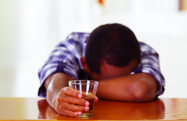 Handsome man wearing white blue shirt sitting by bar counter lying over desk drunk sleeping, alcoholic concept