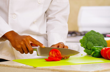 Closeup hands of chef cutting colorful vegetables in professional kitchen, white background