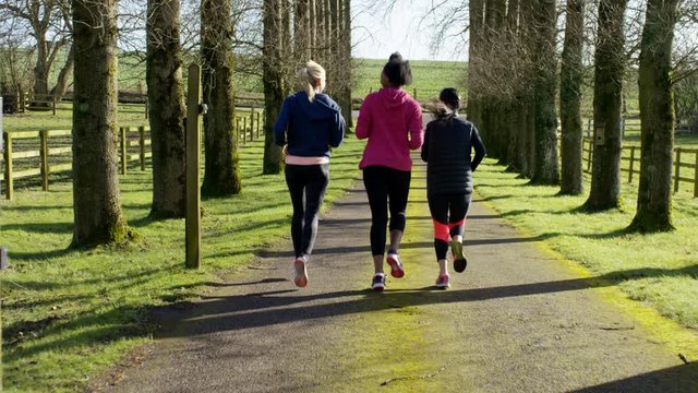  Female friends running together outdoors in the countryside