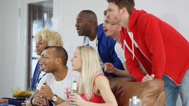  Excited group of friends watching sports game on TV celebrate when team score