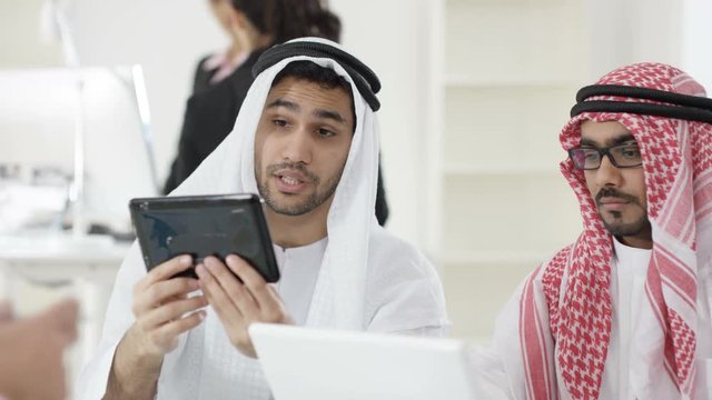  Middle Eastern business group in a meeting, looking at tablet computer