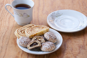 Cup of tea and cookies on a saucer with a roll