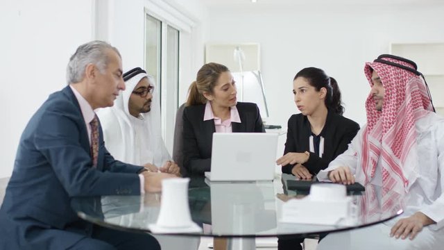  Western businesswomen negotiating in meeting with middle eastern businessmen