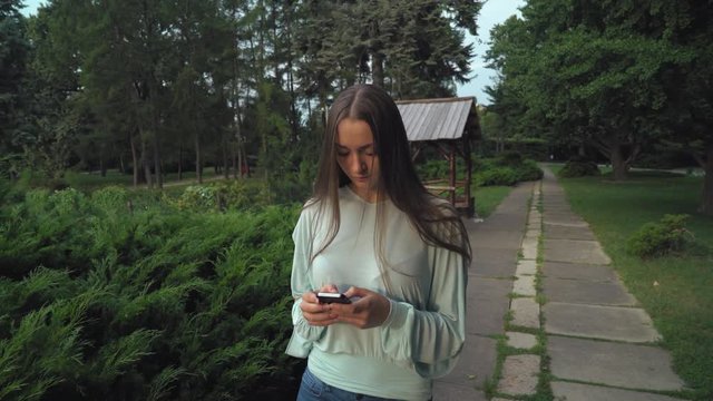 Young slim girl in a green blouse is on track in the park and gaining a message on your mobile phone.