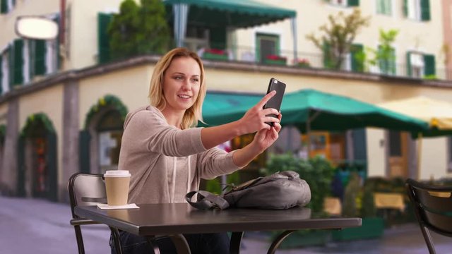 Cute woman taking selfies outside cafe