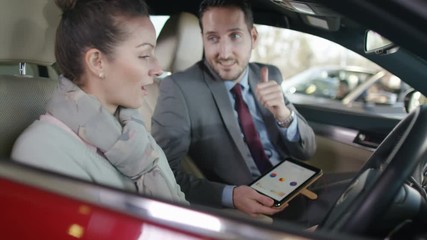  Salesman in car dealership showing customer the interior of new car
