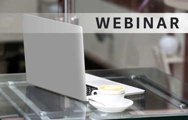Business training concept. View on laptop and a cup of coffee on glass table, close-up