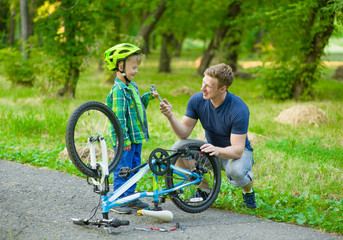 father helping his son bicycle repair