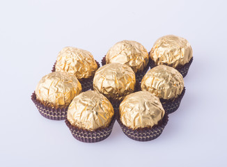 Chocolate ball in a gold foil paper on a background.