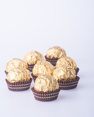 Chocolate ball in a gold foil paper on a background.