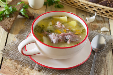 Delicious soup with rice and chunks of meat, rye bread on a wood