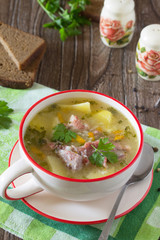Delicious rice soup with pieces of meat and rye bread on a woode