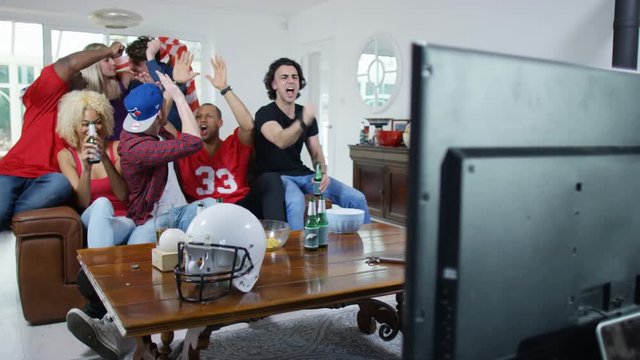  Friends watching American football game on TV celebrate when team scores
