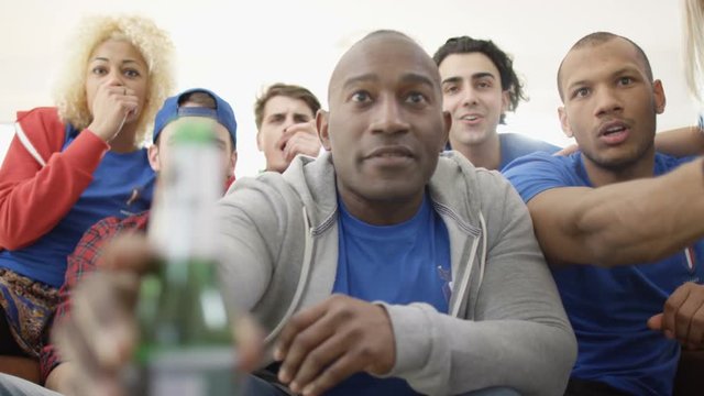  Group of friends watching sports game on TV celebrate when team score