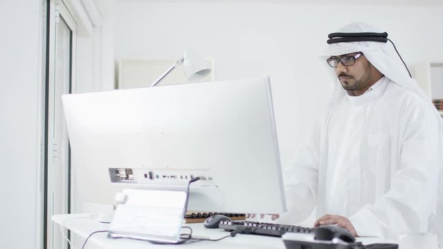  Smiling Arab business man & woman looking at computer in office