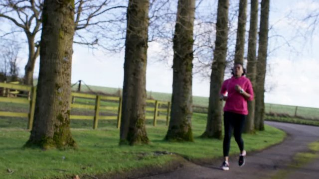  Young woman running in the countryside stops to look at watch