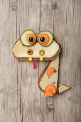 Funny dragon made of bread and cheese on wooden background