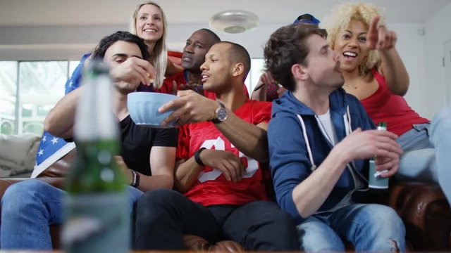 Friends watching American football game on TV celebrate when team scores