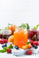 Fototapeta na wymiar assortment of sweet jams and seasonal fruits on white background