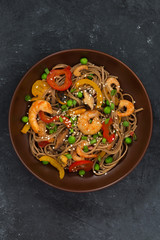Buckwheat noodles with seafood in a bowl on dark background
