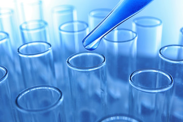 Close up of a pipette dropping a blue sample into a test tube