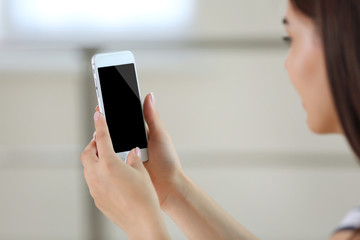 Woman listening to music on smartphone in the room