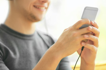 Young man listening to music on smartphone in the room