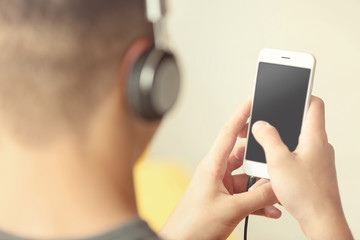 Young man listening to music on smartphone in the room