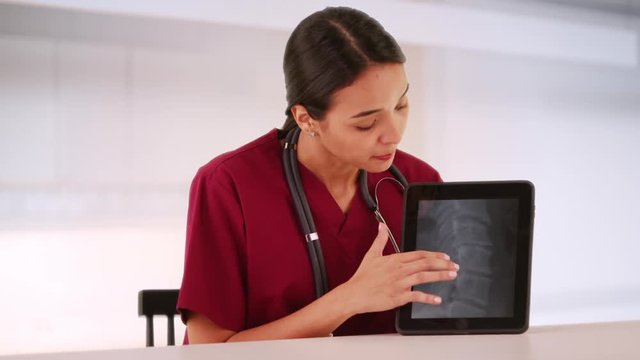 Latino nurse talking about xray on tablet