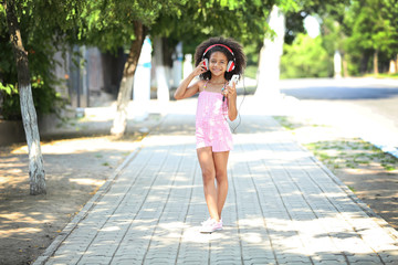 Cute African American girl listening music on street