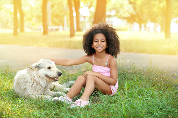 Cute African American girl playing with dog in park