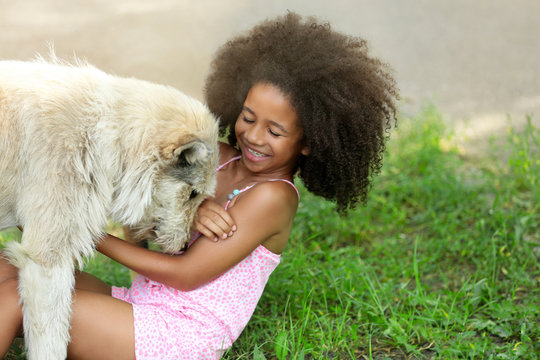 Cute African American girl playing with dog in park