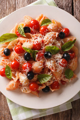 Conchiglie pasta with tomatoes, olives and parmesan cheese closeup. Vertical top view
