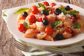 Conchiglie with tomato sauce, olives and parmesan cheese close-up. horizontal
