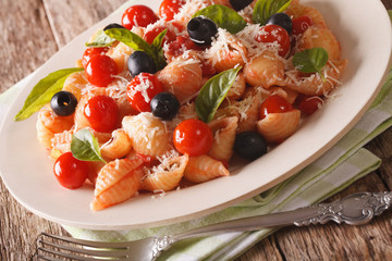 Italian cuisine: Conchiglie pasta with tomatoes, olives and parmesan close-up. horizontal
