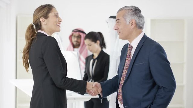  Portrait of smiling Western & Arab business people meeting & shaking hands