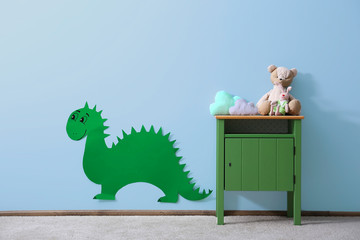 Green bedside table with toys and dinosaur on blue wall background