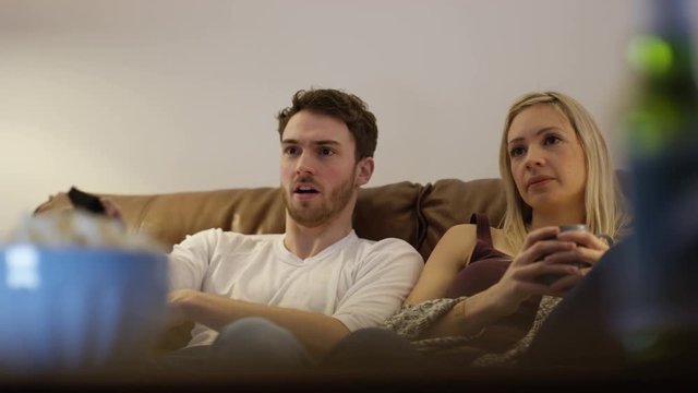  Young couple channel surfing, trying to agree to something to watch on TV