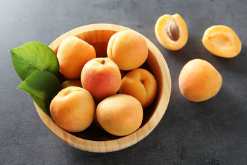 Heap of apricots in wooden bowl on table