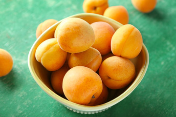 Heap of apricots in bowl on green table